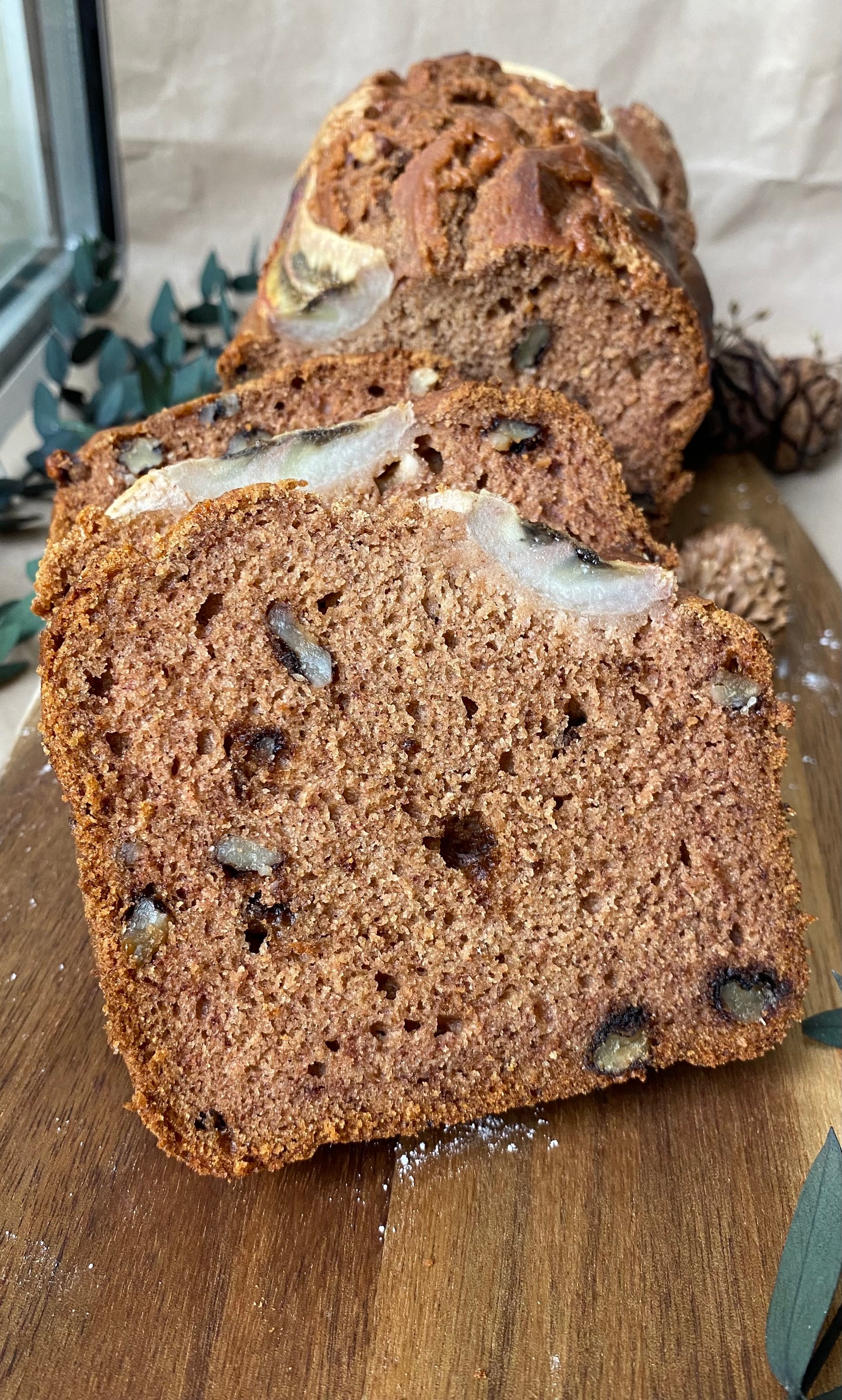 A freshly baked loaf of vegan banana bread, golden brown with visible banana slices and a hint of cinnamon on top.