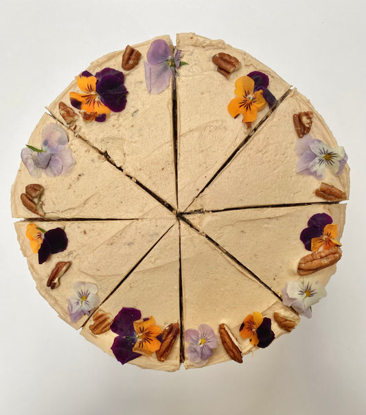 A moist vegan carrot cake, topped with creamy frosting and sprinkled with walnuts.