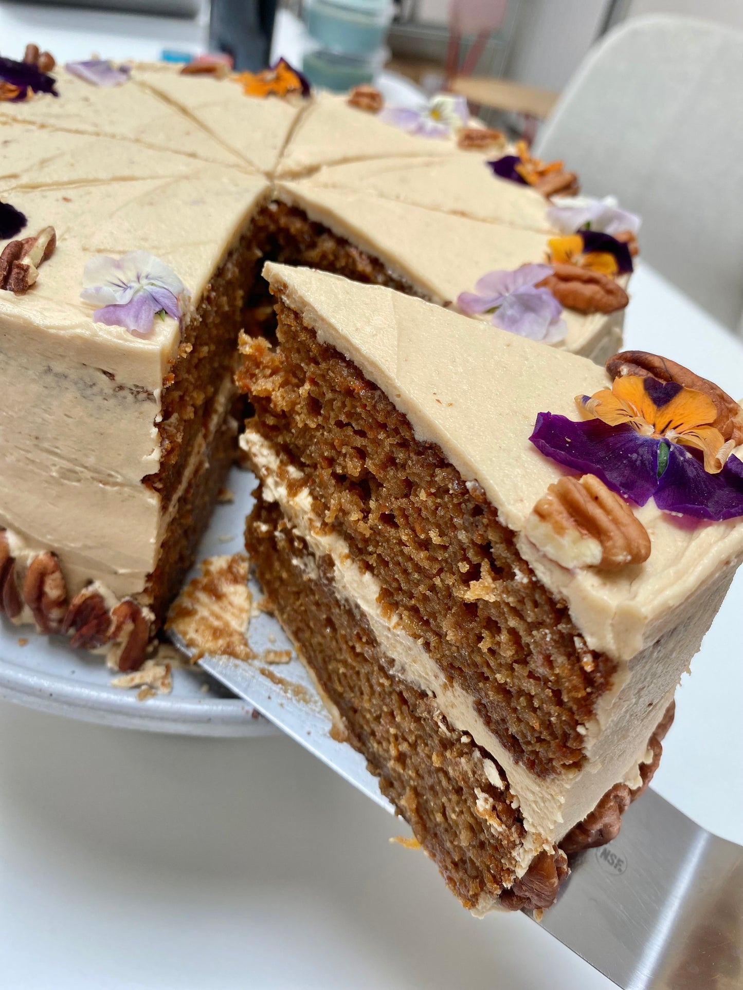 A tempting slice of moist vegan carrot cake, topped with creamy frosting and sprinkled with walnuts.