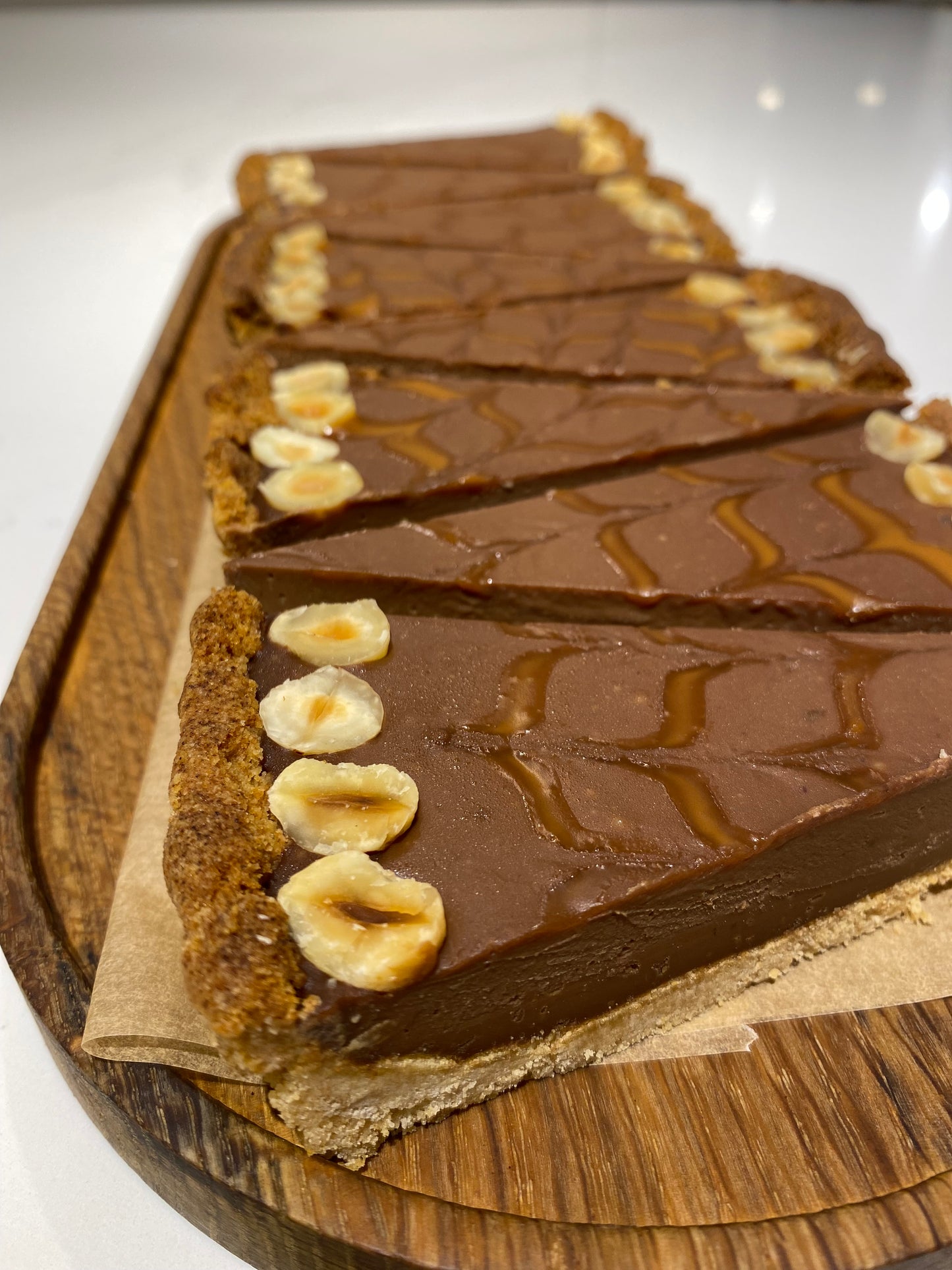 A couple of slices of a decadent vegan chocolate ganache tart on a plate. The rich, dark chocolate filling contrasts beautifully with the golden-brown crust.