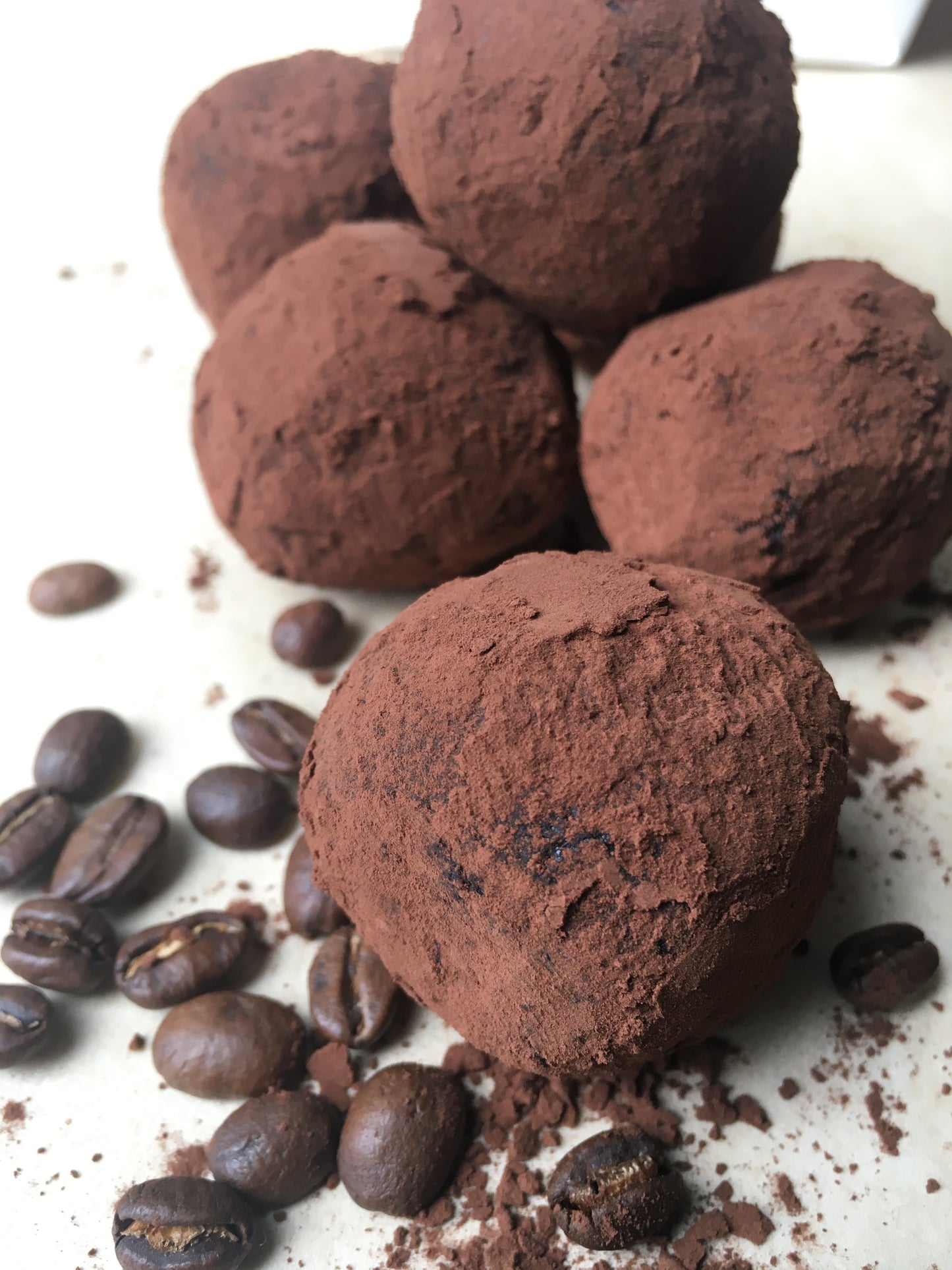 A close-up of several Cacao & Espresso Energy Balls, showcasing their rich, dark chocolate color and textured surface studded with nuts and seeds.