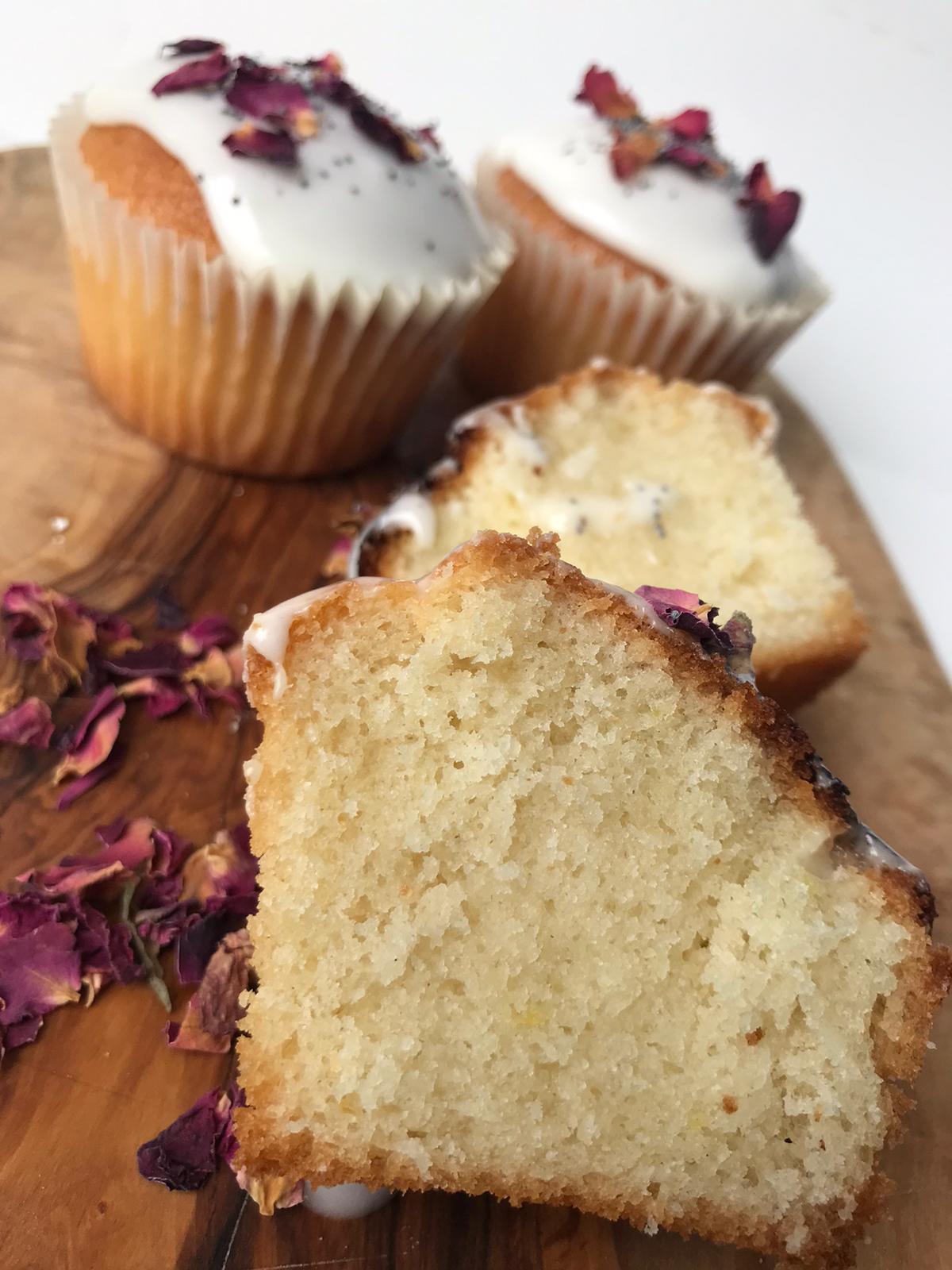 Slice of Five vegan Lemon & Poppy Seed Cupcakes, each with a light yellow top sprinkled with poppy seeds.