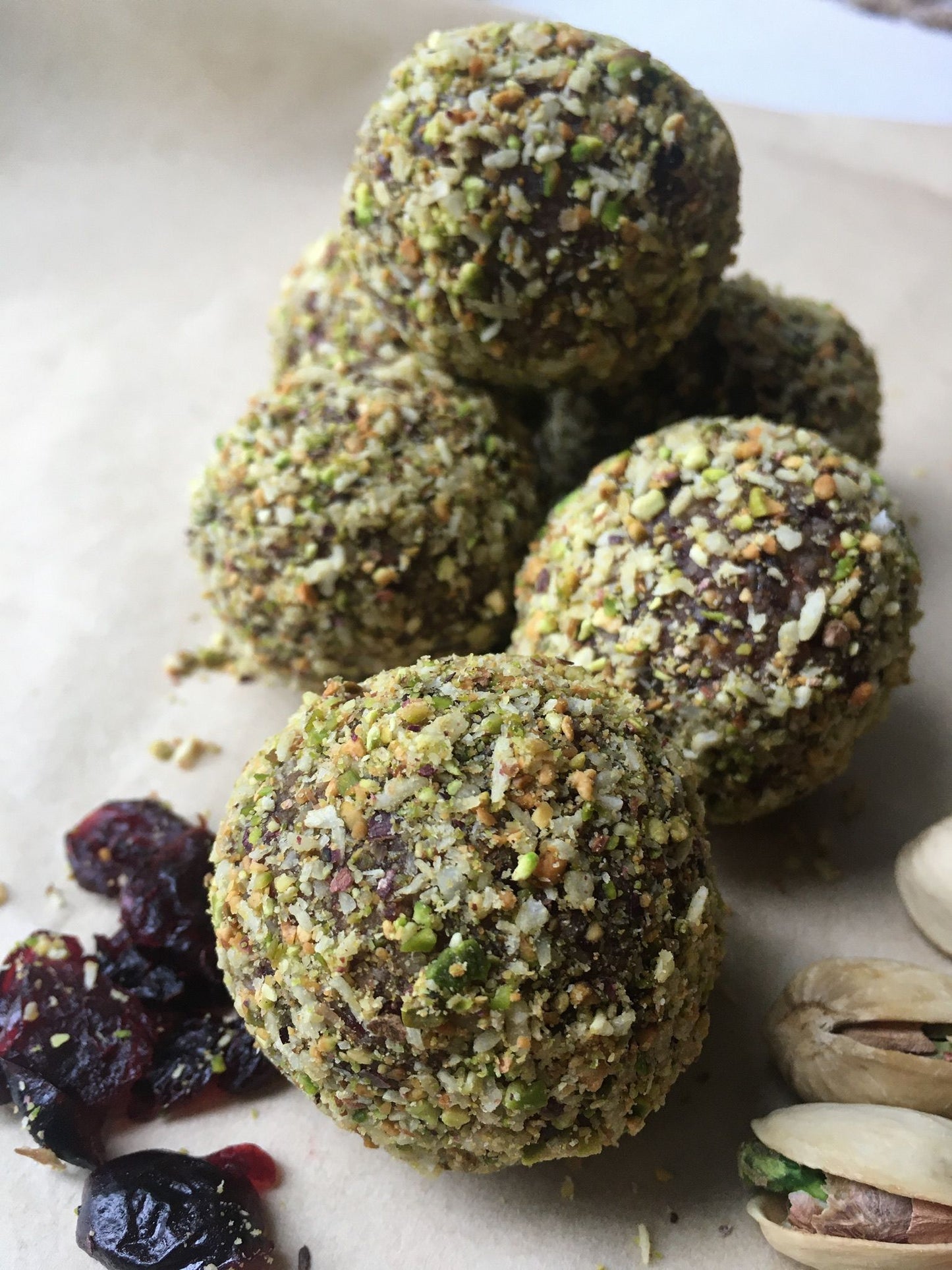 A close-up of several Pistachio & Cranberry Energy Balls, showcasing their vibrant green and red colors from the pistachios and cranberries.