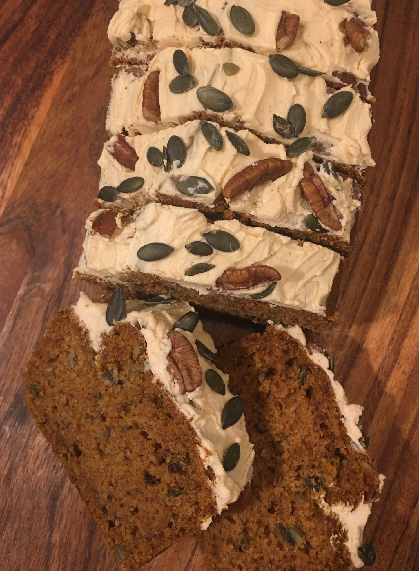 A loaf of moist vegan pumpkin bread, sprinkled with pumpkin seeds and dusted with powdered sugar
