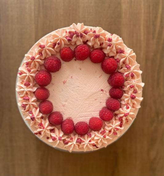 A beautiful vegan raspberry cake, layered with fresh raspberries and topped with a swirl of creamy frosting.