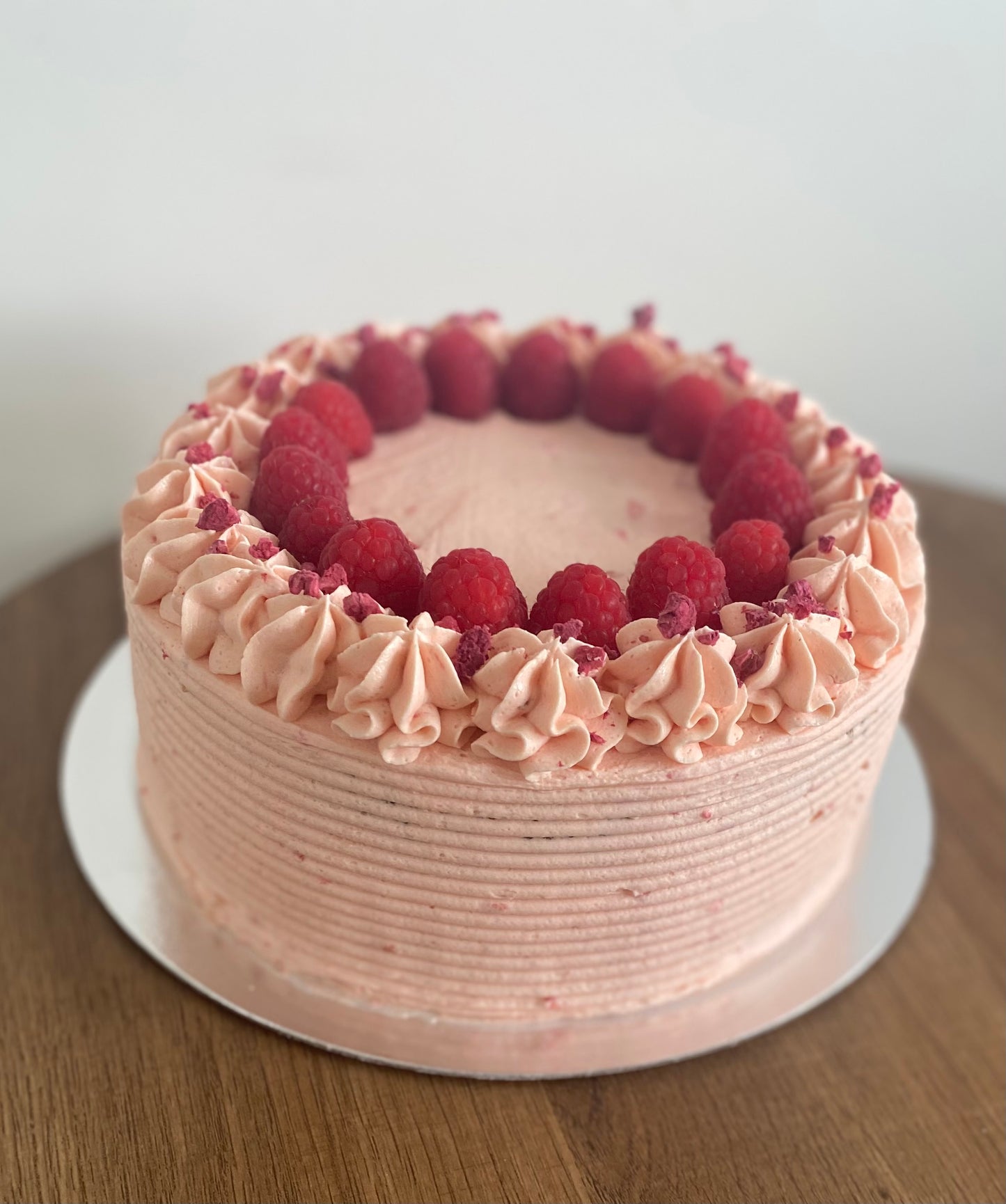 A beautiful vegan raspberry cake, layered with fresh raspberries and topped with a swirl of creamy frosting.