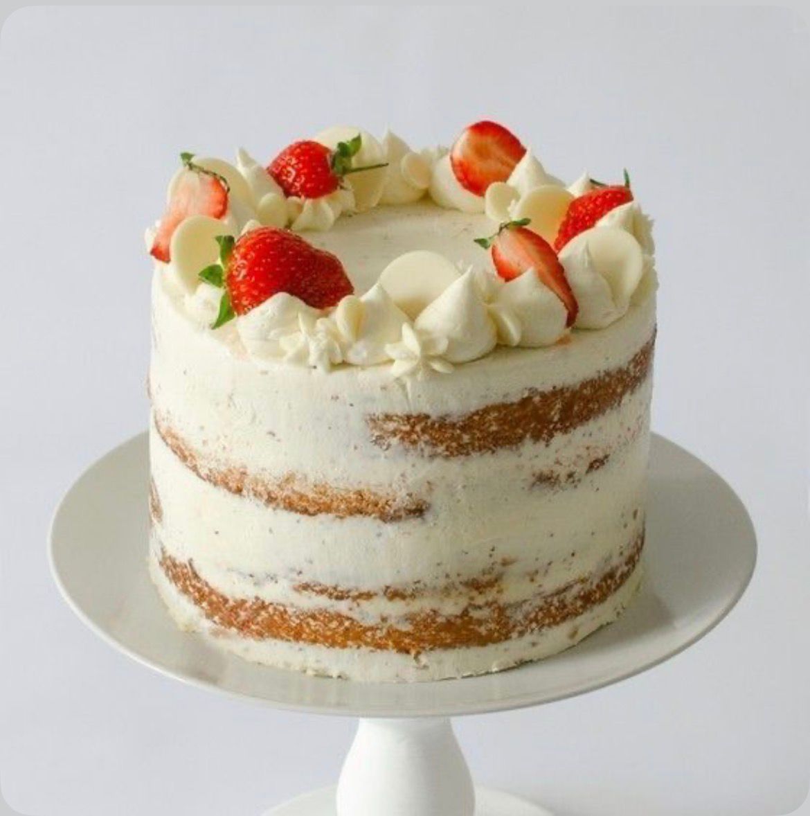 A classic Victoria Sponge Cake, cut in half to reveal a layer of raspberry jam and whipped cream between two fluffy sponge layers, dusted with powdered sugar.